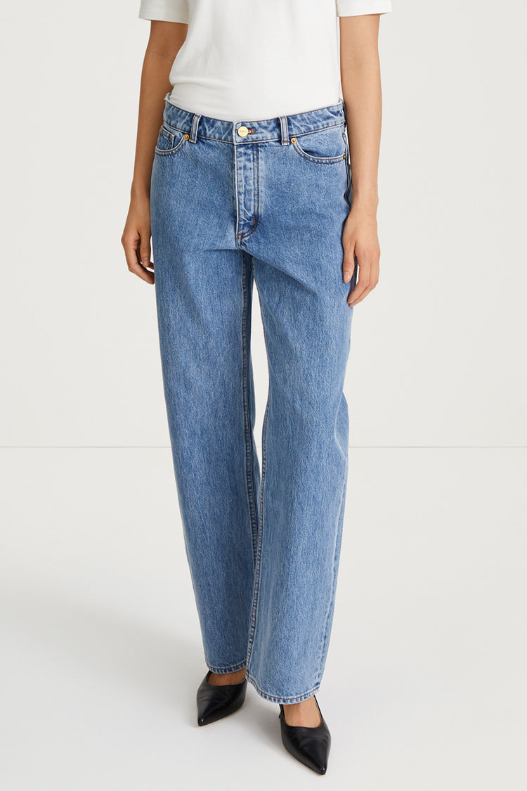 Person wearing blue jeans and a white top on a white background
