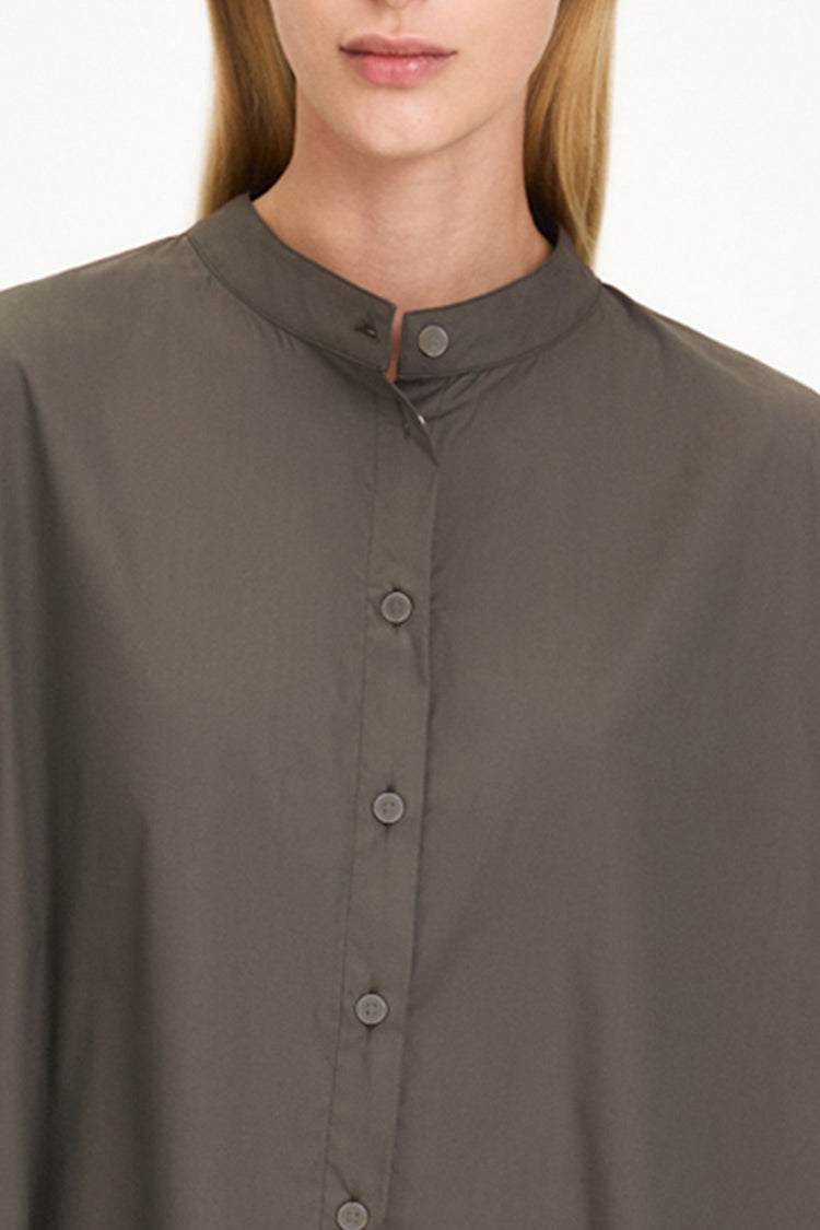 Close-up of a model wearing a dark olive brown button-up shirt with a stand collar and matching buttons.