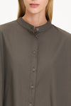 Close-up of a model wearing a dark olive brown button-up shirt with a stand collar and matching buttons.