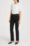 A model wearing a white short-sleeve crewneck t-shirt, black high-waisted straight-leg jeans, and black pointed-toe mule heels, standing against a plain white studio background.