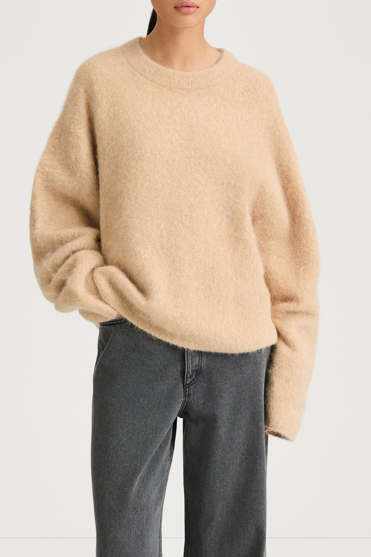 model wearing a beige sweater and gray pants on a white background, stylein, lorena