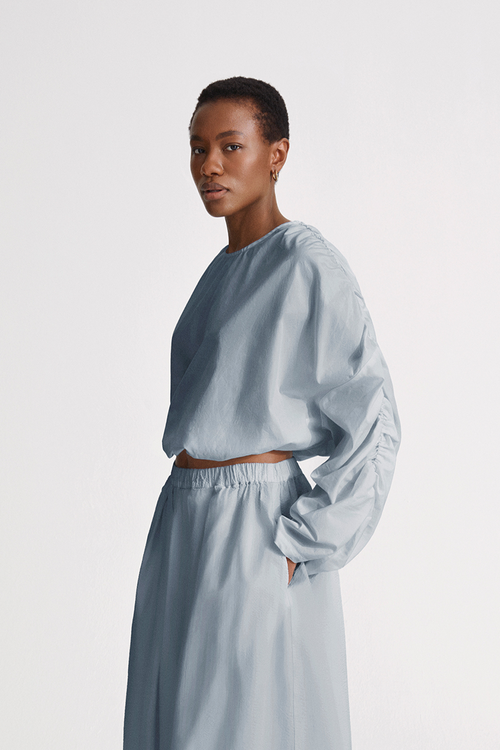 Jennifer top cotton wide long sleeves gathering detail at shoulder seems cropped elastic bottom hem rounded neckline key hole back steel blue stylein side image