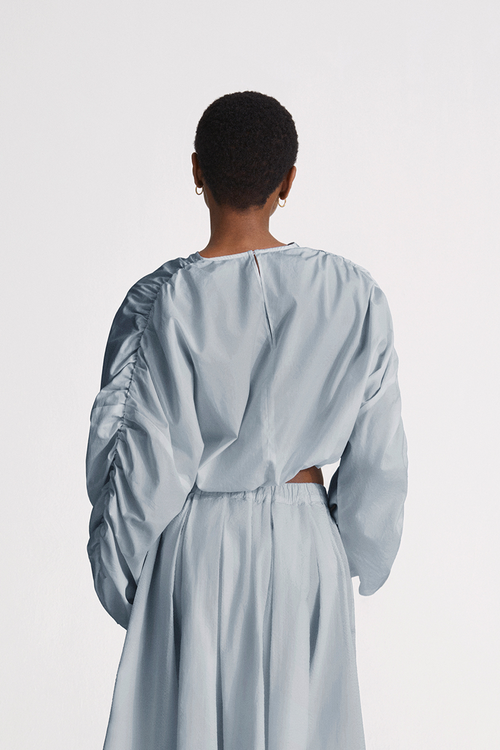 Jennifer top cotton wide long sleeves gathering detail at shoulder seems cropped elastic bottom hem rounded neckline key hole back steel blue stylein back image