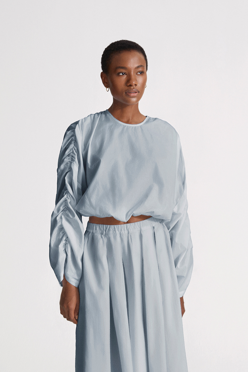 Jennifer top cotton wide long sleeves gathering detail at shoulder seems cropped elastic bottom hem rounded neckline key hole back steel blue stylein front close image